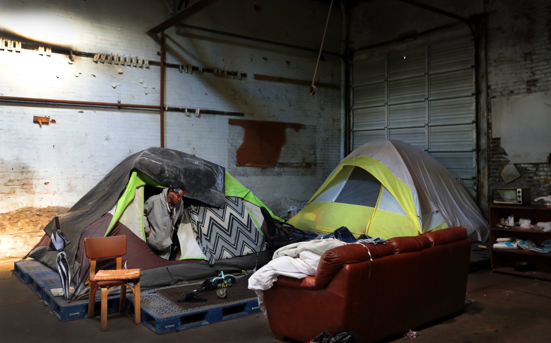 Tents rise under roof of shuttered auto repair shop